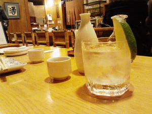 A glass of sake on the rocks with some Tokkuri carafes at an Izakaya setting.
