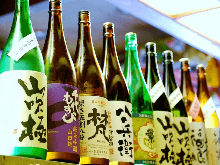 Colorful bottles of sake lined up, each facing forward with its own unique labels.