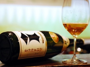 Bottle of Kenbishi sake with a wine glass containing sake.