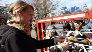someone tying their omikuji to a rack